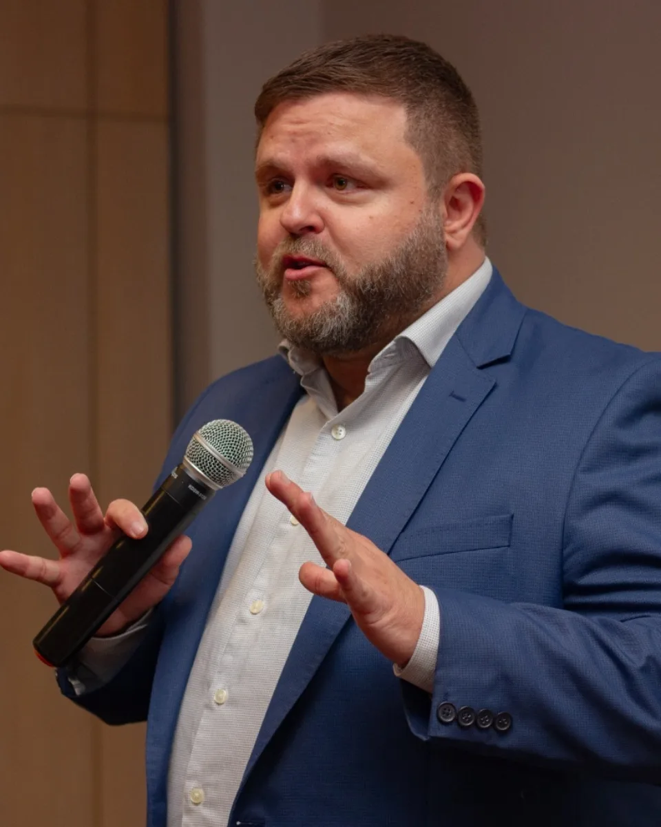 Ronan Mairesse durante uma palestra, com microfone na mão